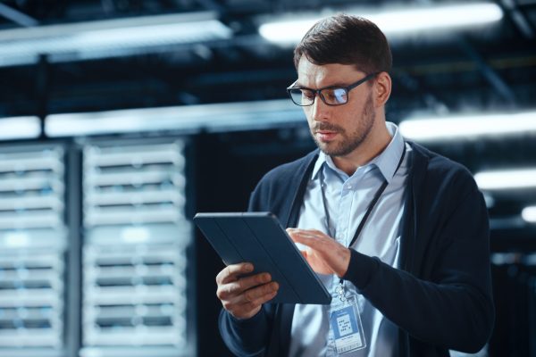 Male,It,Specialist,Walks,Between,Row,Of,Operational,Server,Racks Male,It,Specialist,Walks,Between,Row,Of,Operational,Server,Racks